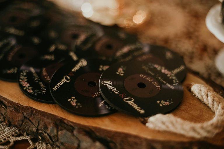 Close-up of personalized wedding coasters with romantic floral design on a wooden surface.