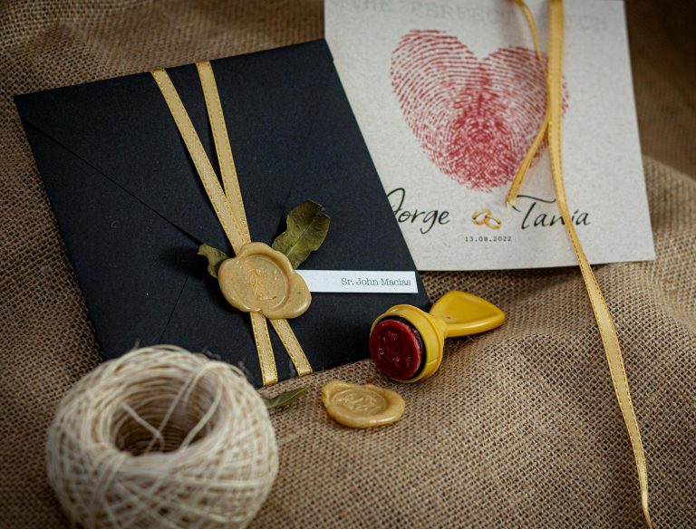 Stylish wedding invitation featuring black envelope, wax seal, and personalized card. Perfect for elegant occasions.